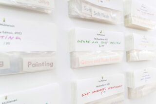 An einer weißen Wand sind mehrere beschriftete Kartenbündel befestigt, auf denen jeweils Titel wie „Genre and Body Review“ und „Light Lavender’s Nightmare“ in verschiedenen Farben stehen.
