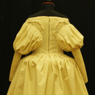 Ein gelbes Ball-Kleid mit großen Puffärmeln auf einer Modellpuppe.