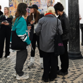 Menschen, die bei einer Veranstaltung in einer Kunstgalerie in einer Gruppe stehen und sich unterhalten.