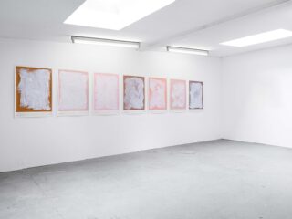 An einer weißen Galeriewand unter Leuchtstoffröhren ist eine Reihe von sieben abstrakten Gemälden mit wirbelnden weißen Mustern auf pastellfarbenem Hintergrund ausgestellt.