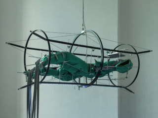 Ein leerer hellgrüner Anzug, eingespannt in einem Metallgestell.