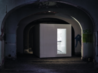 Eine erleuchtete Kammer in einem dunklen, bunkerartigen Raum.