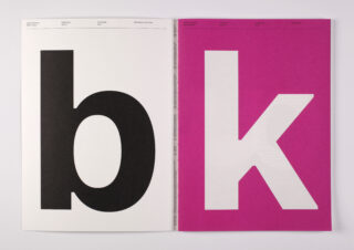 Ein offenes Buch zeigt ein großes schwarzes kleines „b“ auf einer weißen Seite und ein großes weißes kleines „k“ auf einer magentafarbenen Seite.