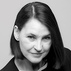 Eine Frau mit glattem, dunklem, schulterlangem Haar blickt mit einem leichten Lächeln in die Kamera. Sie trägt ein dunkles Top und kleine Ohrringe. Das Bild ist schwarz-weiß.