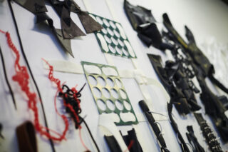 Ein Wanddisplay mit verschiedenen abstrakten ausgeschnittenen Formen, Metallgittern und Drahtgewirr, die in einem geordneten Muster angeordnet sind.