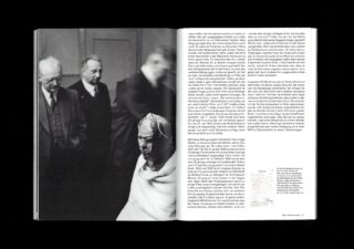 Schwarzweißfoto von drei Männern in Anzügen, die hinter einer sitzenden Person mit bandagiertem Kopf stehen, gezeigt neben einer Seite mit deutschem Text in einer Buchseite.