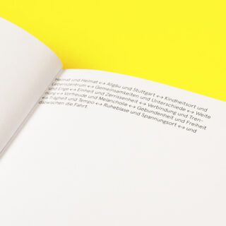 Eine Nahaufnahme eines offenen Buches mit deutschem Text auf einer weißen Seite vor einem leuchtend gelben Hintergrund.