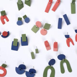 Verschiedene geometrische Ohrringe in Blau, Grün und Rosa auf weißem Hintergrund.