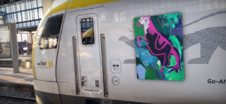 Ein moderner Zug an einem Bahnhof mit einem farbenfrohen Gemälde von Pferden mit kräftigen rosa und blauen Umrissen, das digital auf die Seite gelegt wurde.