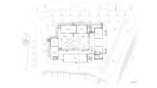 Architektonischer Grundriss eines Gebäudekomplexes mit beschrifteten Räumen, Außenflächen, umliegenden Straßen und nahegelegenen Gebäuden.