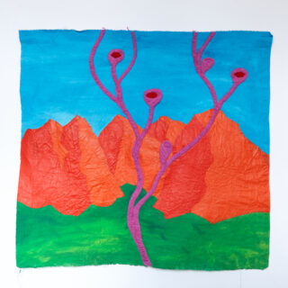 Ein Textilkunstwerk zeigt rote Berge, grüne Hügel und einen blauen Himmel, wobei sich im Vordergrund rosafarbene, rankenartige Formen nach oben erstrecken.