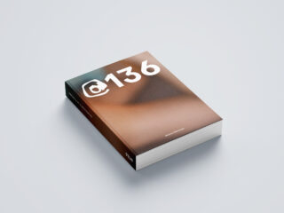 Zu sehen ist ein Taschenbuch mit dem Titel „@136“ und einem unscharfen, braun getönten Cover-Design, das auf einer flachen, hellen Oberfläche liegt.