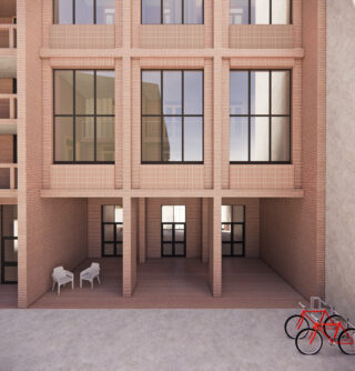 Ein modernes Backsteingebäude mit großen Fenstern, zwei Doppeltüren, zwei weißen Stühlen und einem Tisch sowie zwei roten Fahrrädern, die im Vordergrund an einem Fahrradständer abgestellt sind.