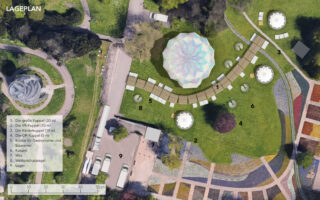 Luftaufnahme eines Parks mit einem Lageplan, der beschriftete Strukturen, Gehwege und Zelte zeigt; auf der linken Seite sind in der deutschen Legende neun Standortmerkmale aufgeführt.