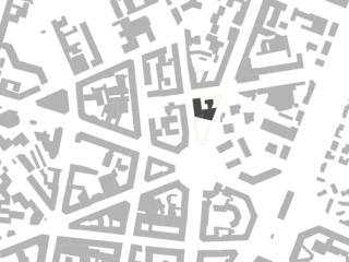 Schwarzweißkarte mit Gebäudegrundrissen; ein zentrales Grundstück ist mit einem gestrichelten orangefarbenen Umriss hervorgehoben und enthält ein schwarz schattiertes Gebäude.