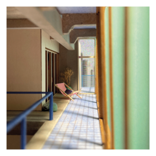 Ein schmaler Balkon mit gefliestem Boden, Liegestuhl, grünem Geländer und Glastüren, auf dem das Sonnenlicht Schatten über die gesamte Länge des Raumes wirft.