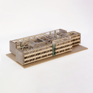 Maßstabsgetreues Modell eines modernen, rechteckigen mehrstöckigen Gebäudes mit gitterartiger Fassade und freiliegenden Innengrundrissen, dargestellt auf einem neutralen Sockel.