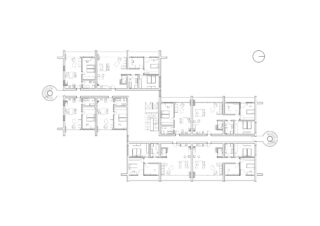 Schwarzweißer Grundriss mit mehreren Räumen, Treppen, Schreibtischen und Besprechungsbereichen und einem Kompasssymbol in der oberen rechten Ecke.