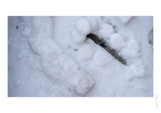 Schneebedeckte Objekte auf dem Boden, darunter ein langer rechteckiger Block und mehrere kleine Schneekugeln, von oben betrachtet.