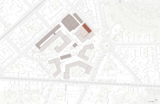 Architektonischer Lageplan mit mehreren rechteckigen Gebäuden, Straßen, einem Kreisverkehr und Grünflächen; ein Gebäude in der Nähe der Mitte ist rot hervorgehoben.
