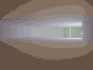 Ein breiter, leerer, sanft beleuchteter weißer Flur mit geschwungenen Wänden und einer schwachen Lichtquelle am anderen Ende.