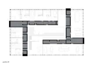 Schwarzweißer Grundriss eines rechteckigen Gebäudes mit mehreren Räumen, dunkelgrau schattierten Fluren und verschiedenen Büromöbelanordnungen.