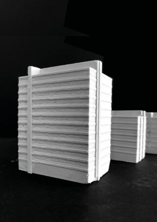 Vor einem schwarzen Hintergrund ist eine weiße, rechteckige, gerippte Modellstruktur zu sehen, wobei im Hintergrund teilweise eine ähnliche, kleinere Struktur sichtbar ist.