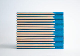 Zwölf angespitzte Bleistifte mit blauen Enden sind horizontal in einem ordentlichen Stapel vor einem schlichten weißen Hintergrund gestapelt.