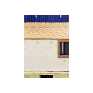 Eine Gebäudefassade weist drei strukturierte Abschnitte auf: oben eine blaue Verkleidung, in der Mitte hellbraune Schindeln mit grünen Punkten und darunter eine cremefarbene Wand mit einem Fenster und weiteren grünen Punkten.