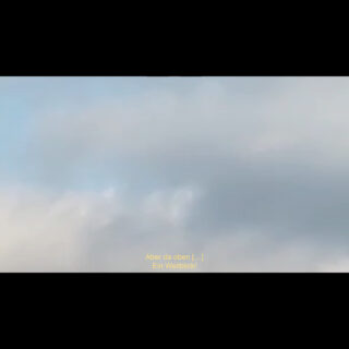 Ein Himmel mit leichten Wolken; unten steht der deutsche Untertitel: „Aber da oben [...] Ein Weitblick!“.
