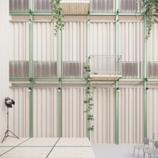 Ein modernes Interieur mit einer gewellten Wand, grünen Stützbalken, hölzernen Balkonplattformen, Hängepflanzen, einem Strahler und ein paar grauen Stühlen.