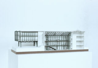 Architekturmodell eines modernen Gebäudeabschnitts mit innerem Stahlrahmen, mehreren Stockwerken und offenen Strukturelementen auf weißem Untergrund.