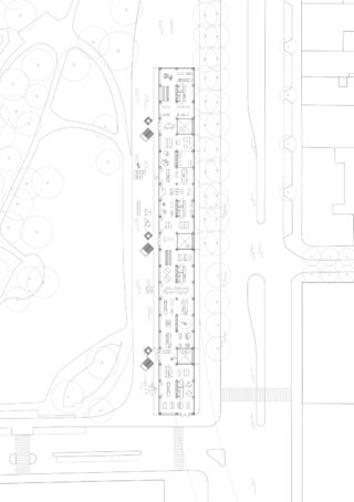 Architektonische Lageplanzeichnung, die ein rechteckiges Gebäude mit Innenräumen, angrenzenden Straßen, Gehwegen, Bäumen und umliegenden Grünflächen zeigt.