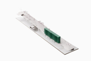 Architekturmodell mit einer langen, weißen Basis mit einer grünen rechteckigen Struktur, verstreuten Bäumen und minimalistischen Merkmalen auf einem schlichten Hintergrund.