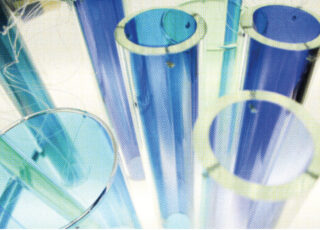 Nahaufnahme mehrerer leerer, transparenter blauer und grüner Reagenzgläser, die aufrecht auf einem weißen Hintergrund angeordnet sind.