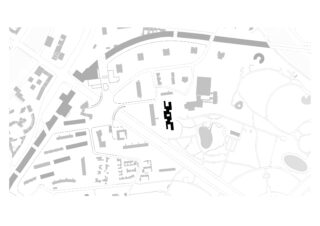 Schwarzer Gebäudegrundriss, hervorgehoben auf einem Lageplan in Graustufen, der Straßen, Gebäude und Grünflächen in einem Stadtgebiet zeigt.