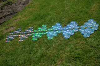 Eine Reihe von Rautesymbolen, die von links nach rechts mithilfe von CDs angeordnet und auf grünem Gras platziert sind.