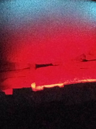 Eine Nahaufnahme zeigt eine Oberfläche mit rotem Licht und Schatten, mit rechteckigen Formen und einem Farbverlauf von Schwarz nach Blau an der Oberseite.