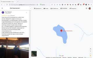 Screenshot einer Google Maps-Seite für den Badesee Fahrenwalde, die eine Karte mit einem See und eine Benutzerbewertung auf Deutsch mit einem Foto von Menschen zeigt, die aus einer hölzernen Vogelbeobachtungshütte hinausschauen.