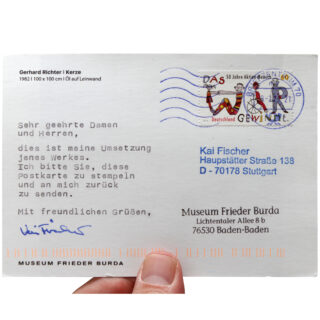 Eine Hand hält eine an Kai Fischer adressierte Postkarte mit getipptem deutschem Text, einer deutschen Briefmarke und einem Logo des Museums Frieder Burda.