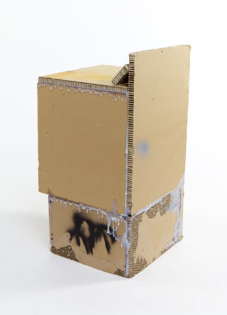 Eine Pappskulptur aus zwei gestapelten Kartons mit aufgemalten und mit weißem Kleber bestrichenen Details, fotografiert vor einem schlichten weißen Hintergrund.