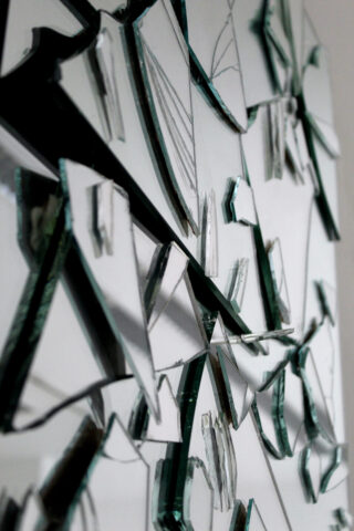 Nahaufnahme unregelmäßig geformter Glasscherben mit scharfen Kanten, angeordnet vor einem weißen Hintergrund.