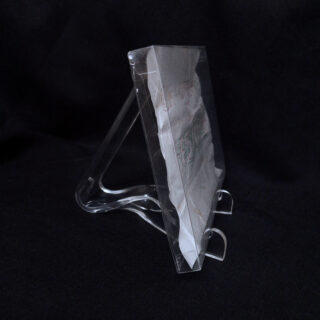 Ein gefaltetes Stück Papier in einer durchsichtigen Plastikhülle wird aufrecht auf einem transparenten Plastikständer vor einem schwarzen Hintergrund präsentiert.