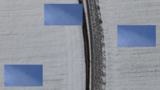 Eine gerade Straße teilt eine schneebedeckte Landschaft, wobei auf beiden Seiten der Straße drei blaue rechteckige Flecken digital über den Schnee gelegt sind.