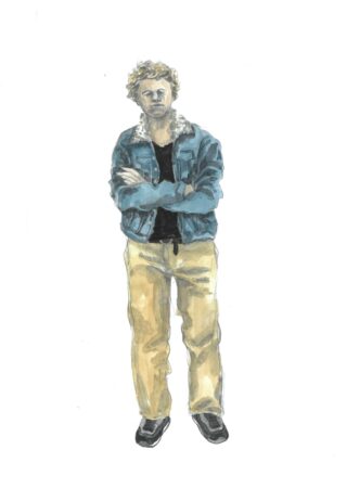 Eine Person steht mit verschränkten Armen da und trägt eine blaue Jeansjacke mit Lammfellkragen, ein schwarzes Hemd, beige Hosen und schwarze Schuhe.