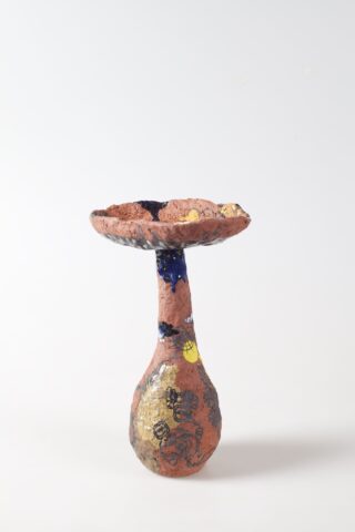 Eine strukturierte, handgefertigte Keramikschale mit breiter, flacher Oberseite und schmaler Basis, verziert mit verschiedenen Farben und abstrakten Mustern vor einem schlichten weißen Hintergrund.