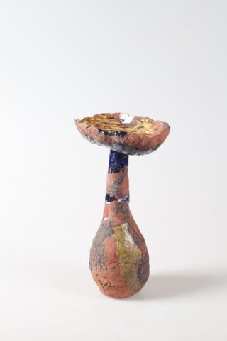 Eine handgefertigte Keramikschale mit strukturierter, mehrfarbiger Oberfläche in Erdtönen und goldenen, blauen und rosa Akzenten, fotografiert vor einem schlichten weißen Hintergrund.