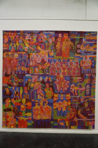 Ein großer, farbenfroher Wandteppich mit abstrakten, menschenähnlichen und organischen Formen in Rot, Orange, Lila und Blau, die in einem gitterartigen Muster angeordnet und an einer weißen Wand angebracht sind.