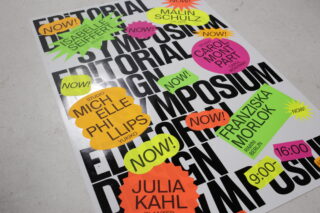 Ein Poster mit der fettgedruckten schwarzen Aufschrift „EDITORIAL SYMPOSIUM“ und farbenfrohen Veranstaltungsdetails, darunter die Namen der Redner, Uhrzeiten und das Wort „NOW!“ auf mehreren Aufklebern.