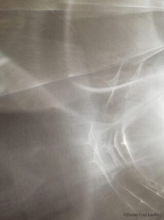 Abstrakte Lichtmuster und Reflexionen auf einer glatten, blassen Oberfläche, die weiche Formen und Farbverläufe erzeugen.